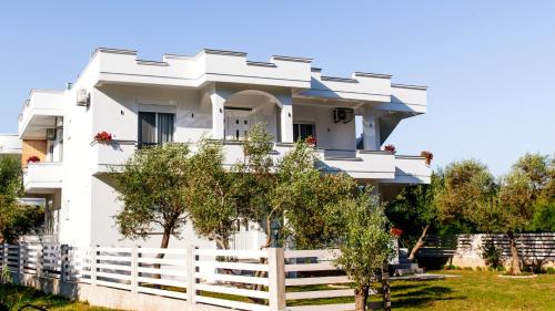 a white house with a white fence and trees at Apartments Hoxha in Ulcinj