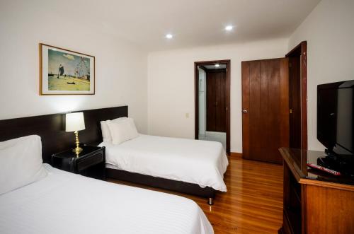 a hotel room with two beds and a flat screen tv at Travelers Condominio Plenitud in Bogotá