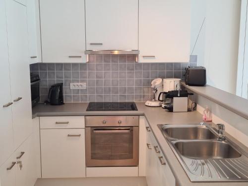 a kitchen with white cabinets and a sink at Oostduinkerke Apartments in Oostduinkerke