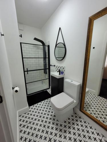 a bathroom with a white toilet and black and white tiles at Room@87 in Ellesmere Port