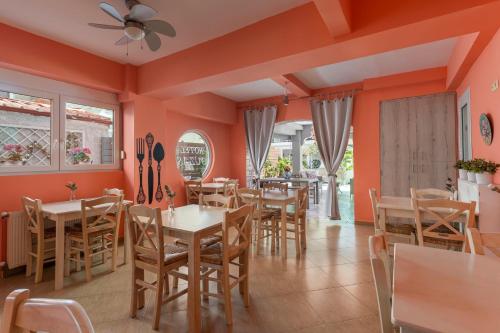a restaurant with orange walls and tables and chairs at Ouzas luxury Hotel in Olympiaki Akti