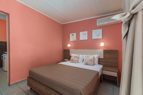 a bedroom with a bed with orange walls at Ouzas luxury Hotel in Olympiaki Akti
