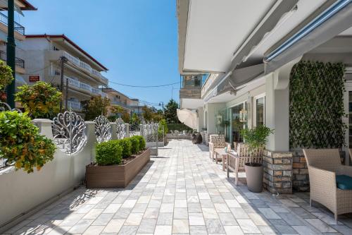 a patio with chairs and plants on a building at Ouzas luxury Hotel in Olympiaki Akti