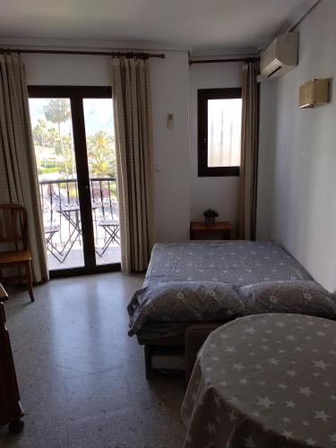a bedroom with a bed and a door to a balcony at Apartamento Parchís con piscina in Denia