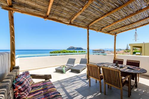patio ze stołem i krzesłami oraz oceanem w obiekcie Ilias Apartments w mieście Platanias