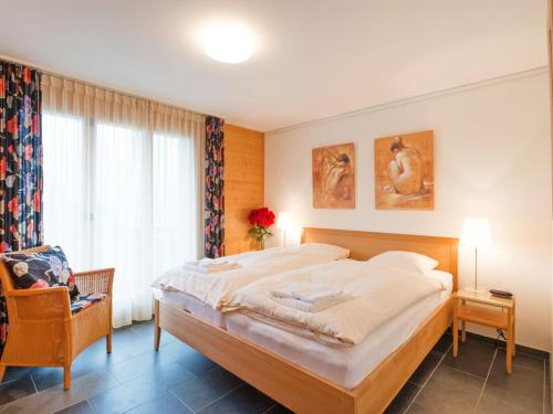 um quarto com uma cama grande e uma cadeira em Apartment Silberhorn-1 by Interhome em Wengen