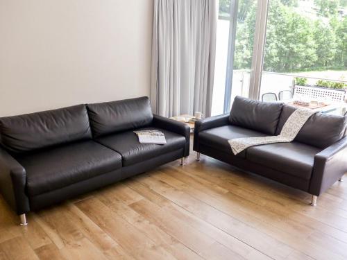 a living room with a black leather couch and a chair at Apartment Amici-3 by Interhome in Saas-Grund