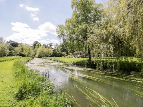 a river in a park with trees and grass at The River House Avon Valley Stonehenge in Salisbury