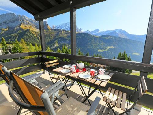 a table and chairs on a balcony with mountains at Apartment Les Petites Maraîches 132-389 by Interhome in Taveyannaz