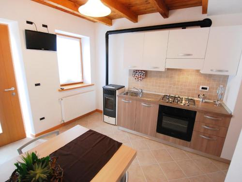 una cucina con armadi bianchi e piano cottura di Holiday Home Albergo Diffuso - Cjasa Ressa by Interhome a Barcis