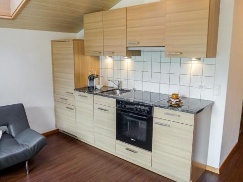 uma cozinha com armários de madeira, um lavatório e um fogão em Apartment Amici-1 by Interhome em Saas-Grund