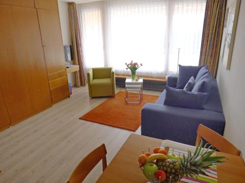 ein Wohnzimmer mit einem blauen Sofa und einem Tisch in der Unterkunft Apartment Promenade - Utoring-59 by Interhome in Arosa