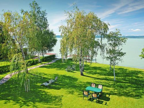 two people sitting on a park bench near the water at Apartment Lakefront 1 by Interhome in Balatonlelle