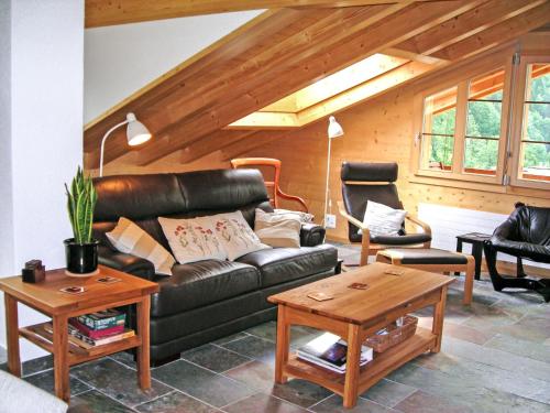 a living room with a black leather couch and tables at Apartment Chalet Pfingsteggblick by Interhome in Grindelwald