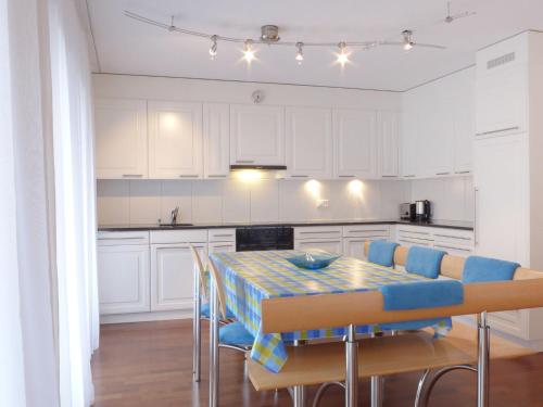 eine Küche mit weißen Schränken sowie einem Tisch und Stühlen in der Unterkunft Apartment Goldenhorn by Interhome in Wengen