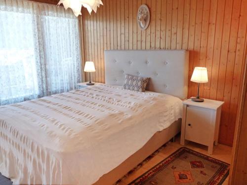 een slaapkamer met een groot wit bed met twee lampen bij Apartment Centaure A RS 3 by Interhome in Ovronnaz