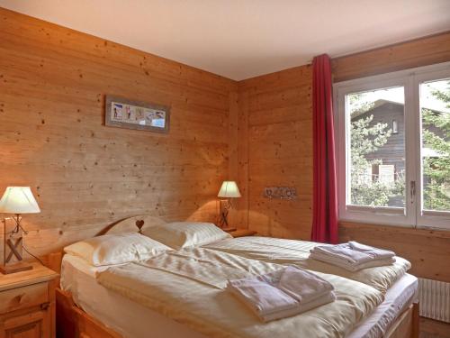 a bedroom with a bed with wooden walls and a window at Apartment Sulegg by Interhome in Wengen
