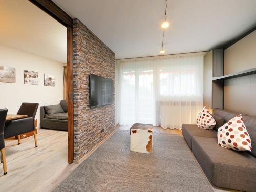 a living room with a couch and a brick wall at Apartment Grillon-3 by Interhome in Zermatt