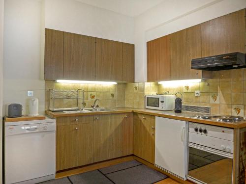 a kitchen with wooden cabinets and a sink and a microwave at Apartment Haus Gertsch Apt-G by Interhome in Wengen