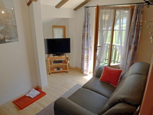ein Wohnzimmer mit einem Sofa und einem Flachbild-TV in der Unterkunft Apartment Heiderösli-3 by Interhome in Grächen