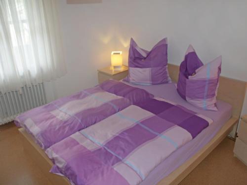 a bed with purple and white sheets and pillows at Apartment Buchenhöhe-2 by Interhome in Resten