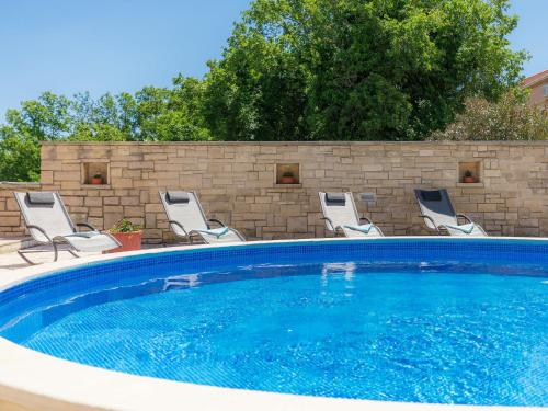 een zwembad met stoelen en een bakstenen muur bij Holiday Home Ljiljana by Interhome in Rakalj