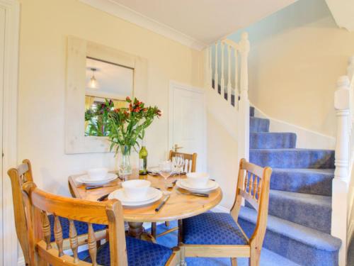 a dining room with a table and chairs and stairs at Holiday Home June Cottage by Interhome in Padstow