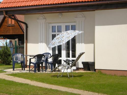 a group of chairs and an umbrella in front of a house at Holiday Home Domek Joanna-3 by Interhome in Łeba