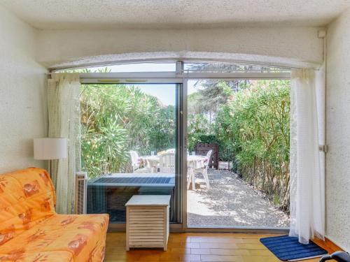 d'un salon avec une porte coulissante en verre s'ouvrant sur une terrasse. dans l'établissement Studio Résidence Green Village 2 by Interhome, au Cap d'Agde
