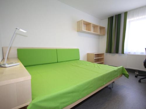 Sankt UlrichにあるApartment smart living by Interhomeの緑のベッド、デスク、窓が備わるベッドルーム1室が備わります。