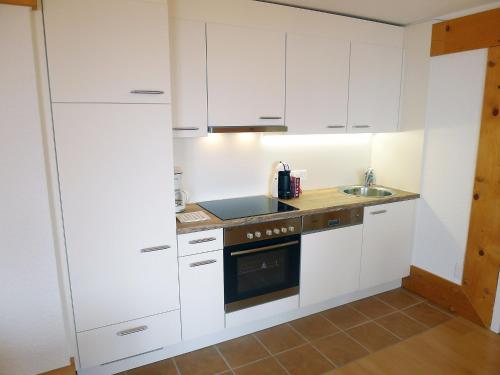 een keuken met witte kasten en een spoelbak bij Apartment Le Bristol C36 by Interhome in Villars-sur-Ollon