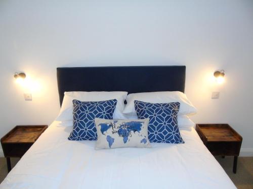1 dormitorio con 1 cama con almohadas azules y blancas en Snug - Sealladh Mara Apartment en Helensburgh