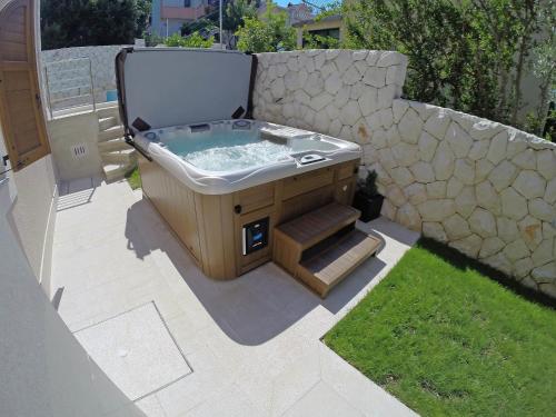 a hot tub in a backyard with a stone wall at Holiday Home Villa Mustra by Interhome in Okrug Donji