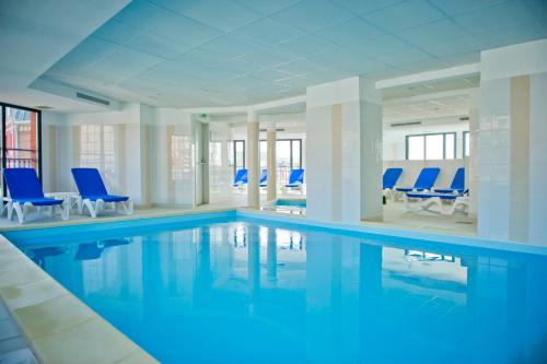 une grande piscine avec des chaises bleues dans un immeuble dans l'établissement Résidence Goélia Belle Epoque, à Mers-les-Bains