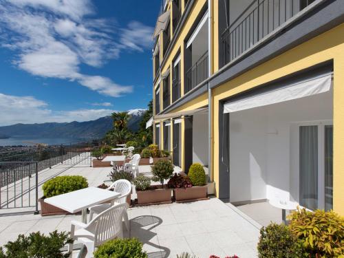 a patio with white tables and chairs on a building at Hotel Stella SA in Locarno
