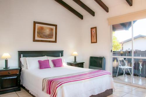 a bedroom with a large bed with purple pillows at Bad-wiessee Apart Hotel & Spa in Villa General Belgrano