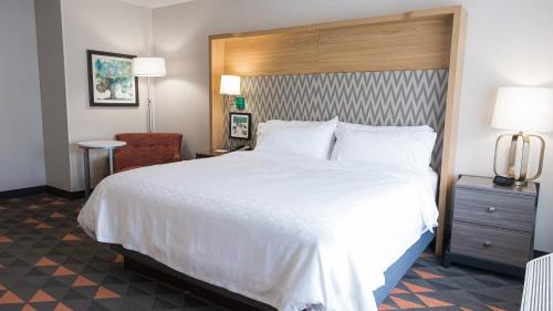 a hotel room with a large bed and a chair at Holiday Inn & Suites Philadelphia W - Drexel Hill by IHG in Drexel Hill