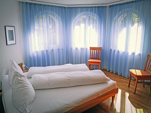 a bedroom with two beds with blue curtains and a chair at Apartment Edelweiss A-3 by Interhome in Leukerbad