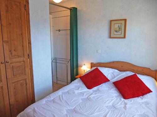 a bedroom with a white bed with two red pillows at Apartment Oisans 37 by Interhome in Les Menuires