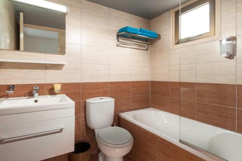 a bathroom with a toilet and a tub and a sink at Penelope Beach Hotel Apts in Protaras