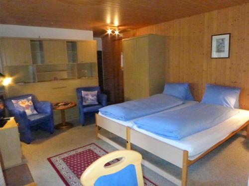 - une chambre avec un lit et deux chaises bleues dans l'établissement Apartment Lohnerhus-2 by Interhome, à Grindelwald