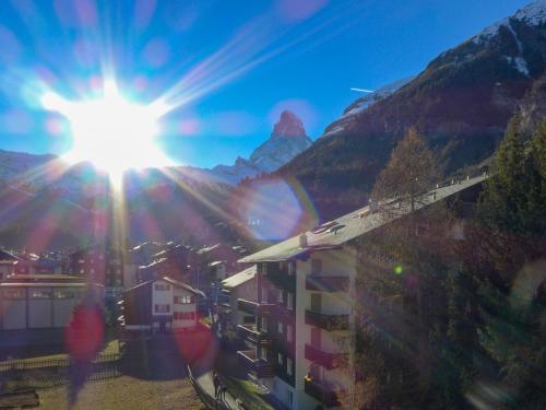 a view of a city with the sun in the sky at Apartment Imperial-10 by Interhome in Zermatt