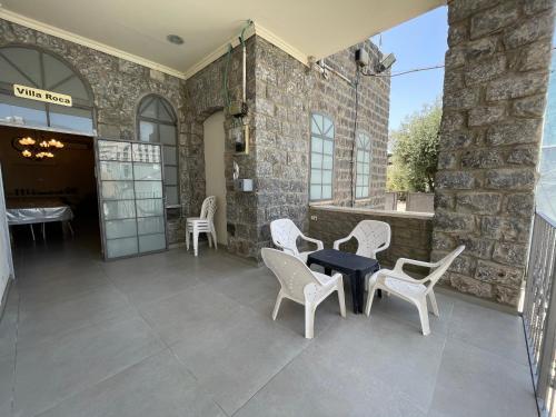a patio with white chairs and a black table at Puy Villa Roca Tiberias in Tiberias