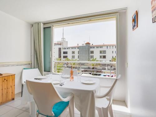 une salle à manger avec une table et des chaises blanches ainsi qu'une grande fenêtre dans l'établissement Studio Le Sunset-Cap Sud-16 by Interhome, au Cap d'Agde