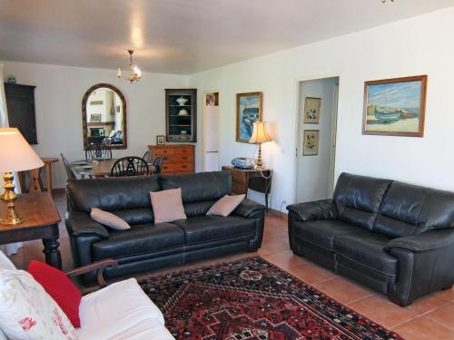 ein Wohnzimmer mit einer schwarzen Ledercouch und einem Tisch in der Unterkunft Holiday Home Villa Brigantin by Interhome in Plage dʼArgelès