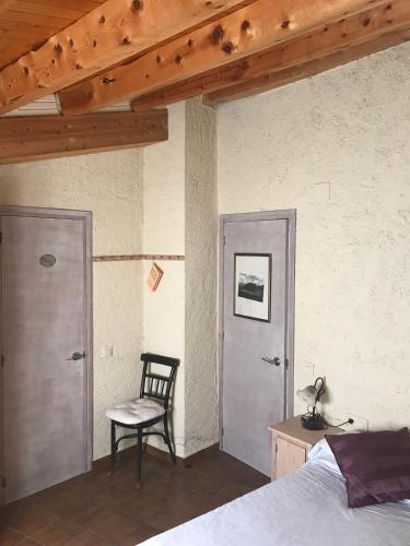 a bedroom with a bed and a chair next to two doors at Cal Gabriel in Tuixen