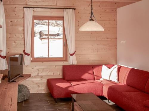 ハイリゲンブルートにあるChalet Glockner by Interhomeのリビングルーム(赤いソファ、窓付)