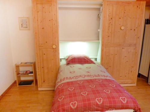 a bedroom with a bed and two wooden cabinets at Studio Sources 4109 by Interhome in Ovronnaz