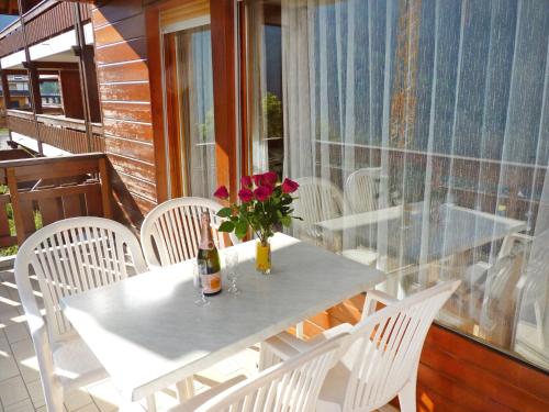 a table with a bottle of wine and flowers on a balcony at Studio Les Sources 4109 by Interhome in Ovronnaz