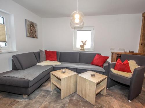 uma sala de estar com um sofá cinzento e almofadas vermelhas em Holiday Home Machreich by Interhome em Hundsdorf